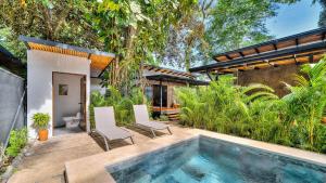 an outdoor swimming pool with two chairs and a house at Salt n Pepper - Rosemary Villa with shared Pool - Adults Only in Puerto Viejo