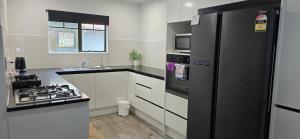 a kitchen with a black refrigerator and a stove at Baden Lodge Motel - PRIVATE SPA Bath in Rotorua