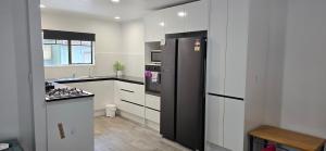 a kitchen with a black refrigerator and a stove at Baden Lodge Motel - PRIVATE SPA Bath in Rotorua