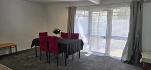 a dining room table with red chairs and a window at Baden Lodge Motel - PRIVATE SPA Bath in Rotorua