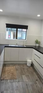 a white kitchen with a sink and a window at Baden Lodge Motel - PRIVATE SPA Bath in Rotorua +19 photos