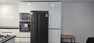 a black refrigerator in a kitchen with white cabinets at Baden Lodge Motel - PRIVATE SPA Bath in Rotorua +27 photos