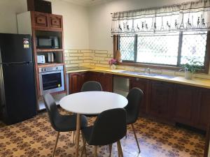 een keuken met een tafel, stoelen en een koelkast bij Relaxing Vintage Cottage in Corrimal
