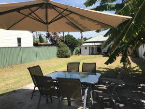 een tafel en stoelen onder een grote parasol bij Relaxing Vintage Cottage in Corrimal