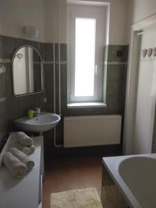 a bathroom with a sink and a tub and a mirror at Anna Apartmanok in Pécs