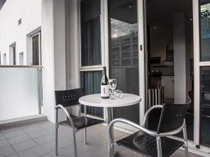 a table with a bottle of wine and two chairs at Richmond Central Apartments in Melbourne
