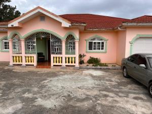 Una casa rosa con un coche aparcado delante. en KoolVille, en Mandeville
