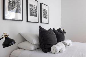 Privately Managed Golf View - Bangalay Villas في Shoalhaven Heads: غرفة نوم مع سرير مع وسائد سوداء وبيضاء +20 صورة