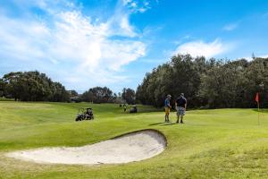 Privately Managed Golf View - Bangalay Villas في Shoalhaven Heads: شخصين واقفين على ملعب قولف