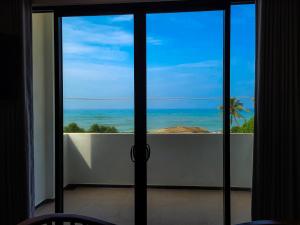 a view of the ocean from a room with sliding glass doors at Lavinia Beach Hotel Ambalangoda in Ambalangoda
