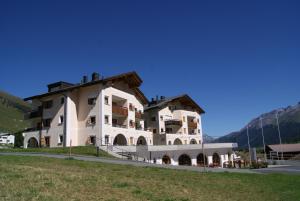 a large white building with a mountain in the background at Ferienwohnungen Hotel Allegra in Zuoz