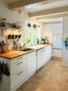 a kitchen with white cabinets and a wooden counter top at Idyllic Country House Overlooking Svanninge Hills in Millinge
