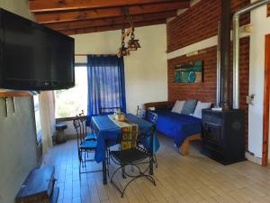 a living room with a blue table and a bed at Cabañas Ojos de Cielo in Santa Rosa de Calamuchita