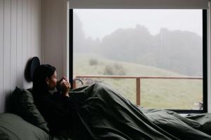 een vrouw die op een bed zit en uit een raam kijkt bij Tiny Oscar in Robertson