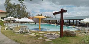 a pool with tables and umbrellas and a cross at Flat Paz & Relax Monte Castelo 1809 in Sairé