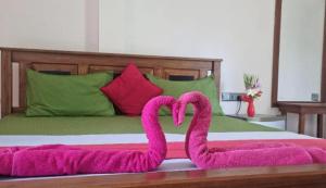 two pink flamingos laying on top of a bed at Secret Hill Haven in Unawatuna