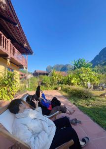 Twee mannen liggen op een bankje op een terras. bij ThongDong Homestay in Hữu Lũng