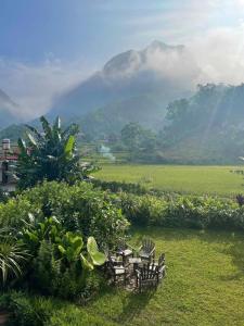 een tafel en stoelen in een veld met een berg bij ThongDong Homestay in Hữu Lũng +4 foto's