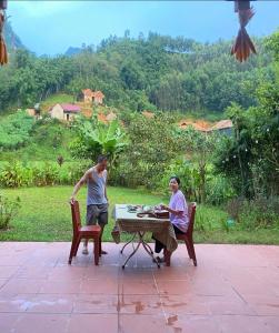 two men sitting at a table on a patio at ThongDong Homestay in Hữu Lũng +4 photos