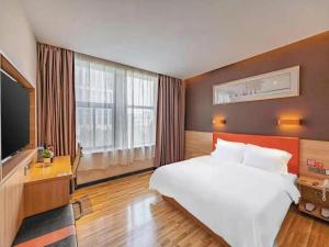 ein Hotelzimmer mit einem großen Bett und einem Fernseher in der Unterkunft 7Days Premium Nanjing Olympic Sports International Exhibition Center in Nanjing