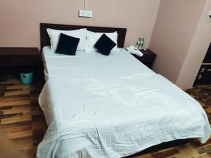 a large bed with white sheets and pillows at Hotelroyalcrown in Jāmb +2 photos