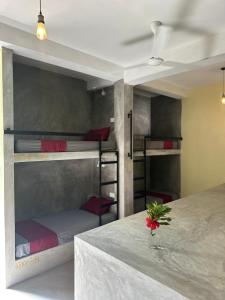 a room with three bunk beds and a table with a flower at Pranaya Hiriketiya in Hiriketiya