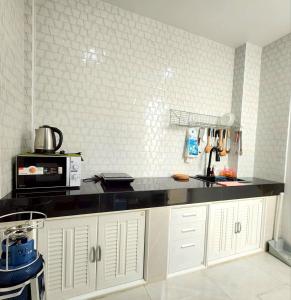 a kitchen with white cabinets and a black counter top at Konijiwa Bangsaen Private Pool Karaoke BBQ in Ban Muang (1)