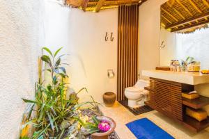 a bathroom with a toilet and some plants in it at Santai Hotel in Amed
