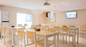 a dining room with white tables and chairs at City Comfort Inn Wuhan Guanggu Software Park in Wuhan