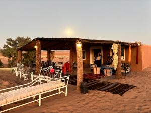 a house in the desert with beds in front of it at Bivouac La Dune Blanche in Mhamid