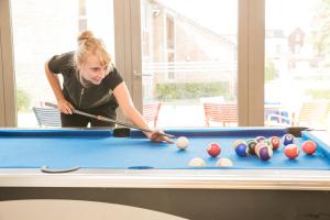 une femme jouant au billard dans l'établissement Hostel Europa, à Bruges