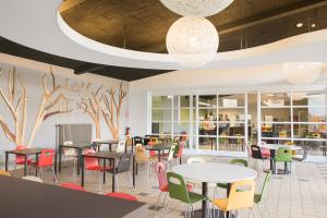 a dining room with tables and chairs and trees on the wall at Hostel Europa in Bruges