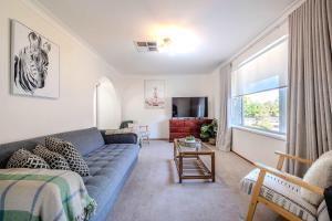 a living room with a blue couch and a window at Daisy's Lodge - Relaxed & Family-Friendly Stay in Dubbo