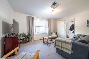 a living room with a couch and a tv at Daisy's Lodge - Relaxed & Family-Friendly Stay in Dubbo