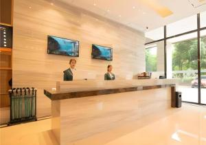 City Comfort Inn Changsha Outlets Datuo Metro Station في تشانغشا: رجلان يجلسان على مكتب الاستقبال مع جهاز كمبيوتر محمول