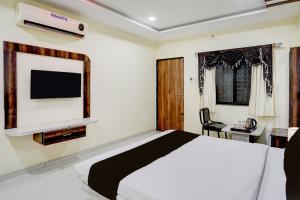 Collection O Daulatabad Fort Aurangabad Formerly JVS Park Inn في Daulatābād: غرفة نوم بها سرير وتلفزيون على الحائط