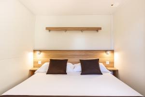 een slaapkamer met een wit bed en 2 bruine kussens bij Hotiday Otranto Porto in Otranto