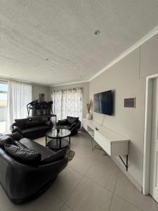 una sala de estar con 2 sofás negros y una mesa. en Unit 32 Ongwe, en Swakopmund
