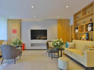 GreenTree Esports Hotel Qingdao Licang District Wanda في Laoshan: غرفة انتظار مع أريكة وكراسي وتلفزيون