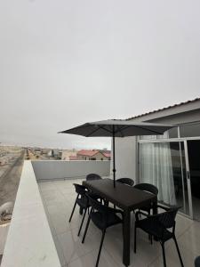 Una mesa negra con sillas y una sombrilla en un techo. en Unit 32 Ongwe, en Swakopmund