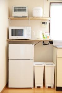 a kitchen with a microwave and a refrigerator at MINI HOTEL totonoi ロウリュ式サウナのある静かな平屋 in Shimonoseki
