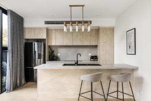 a kitchen with a counter with two stools and a refrigerator at Ivanhoe Five Luxury Holiday Home 4 Bed Sleep 6 in Melbourne +12 photos