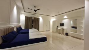 a bedroom with a blue bed and a ceiling fan at Aagneyam Grand Resort in Kozhikode
