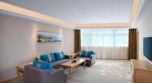 a living room with blue chairs and a television at Vienna Hotel Shandong Dezhou Government Shopping Plaza in Songguantun