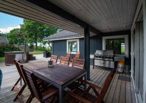 a deck with a wooden table and chairs and a grill at Cottage With Panoramic View Of Lammefjorden in Holbæk