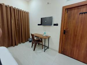 a room with a table and a tv and a wooden door at Hotel Soni Indore in Indore