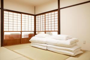 a room with a bed with white pillows and windows at MINI HOTEL totonoi ロウリュ式サウナのある静かな平屋 in Shimonoseki