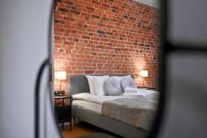 a bedroom with a bed with a brick wall at Szeroka Residences in Toruń