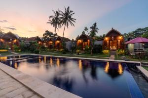 an image of a villa with a swimming pool at dusk at Arta Bali Glamping in Tianyar