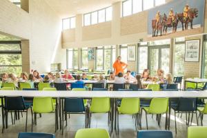 an image of a classroom with children sitting around a large table at Jeugdherberg De Peerdevisser in Oostduinkerke